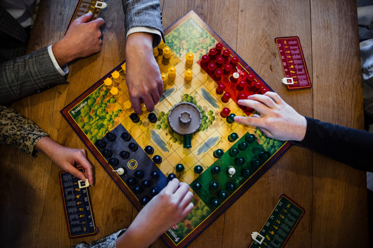 A board game and hands seen from above.