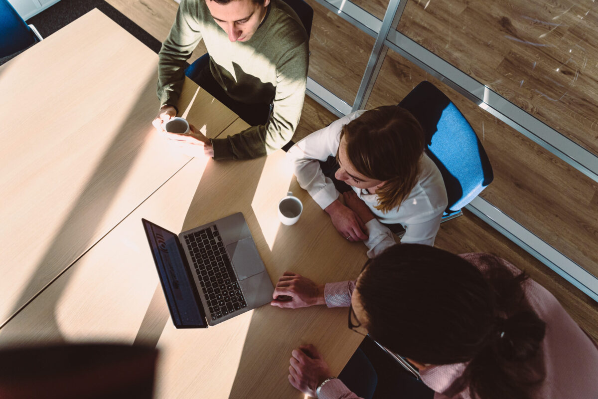 Three people around a laptop, seen from above.
