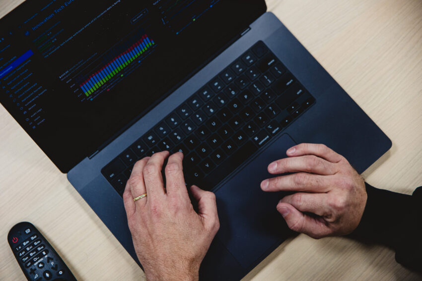 A laptop with hands on the keyboard, seen from above.