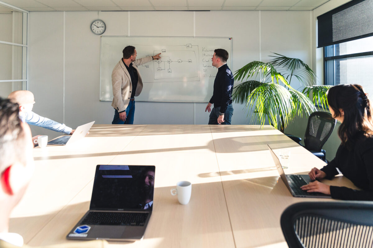 People in a meeting room. Two people standing in front of a whiteboard.