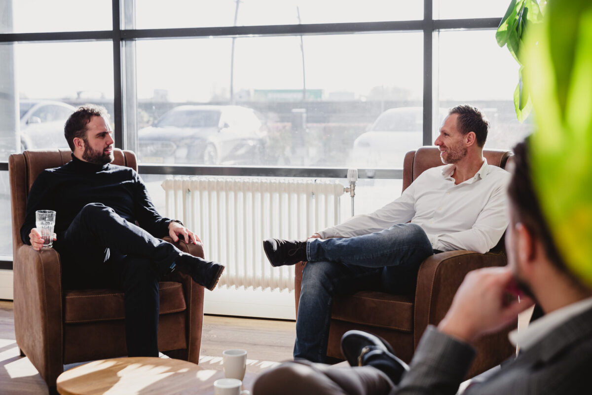 Two people in a chair talking, one person in front.