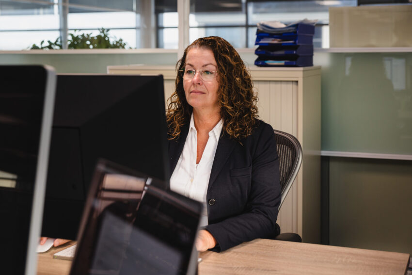 A person at her desk working on her laptop.