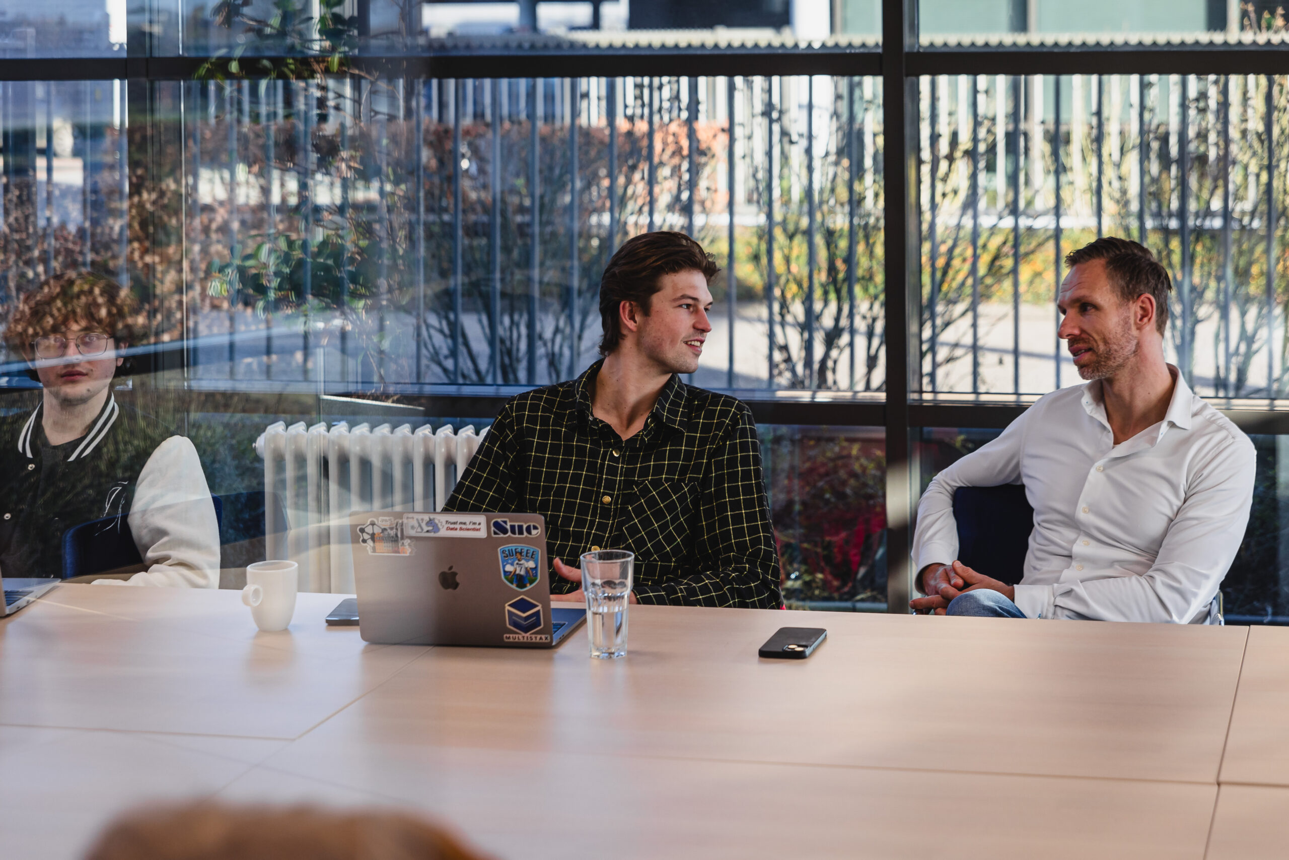 Three people in a meeting room.