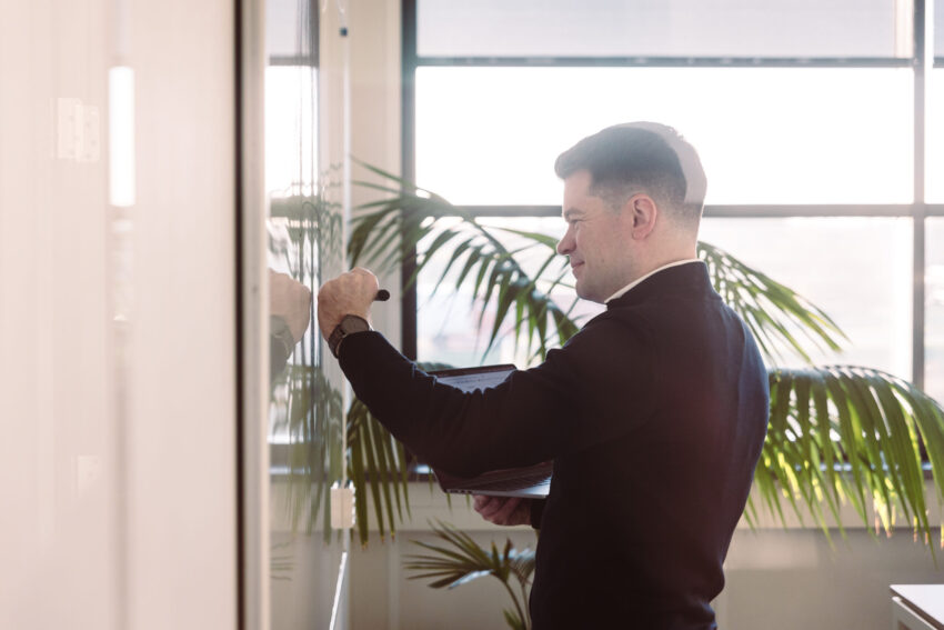 A person in front of a whiteboard, writing.