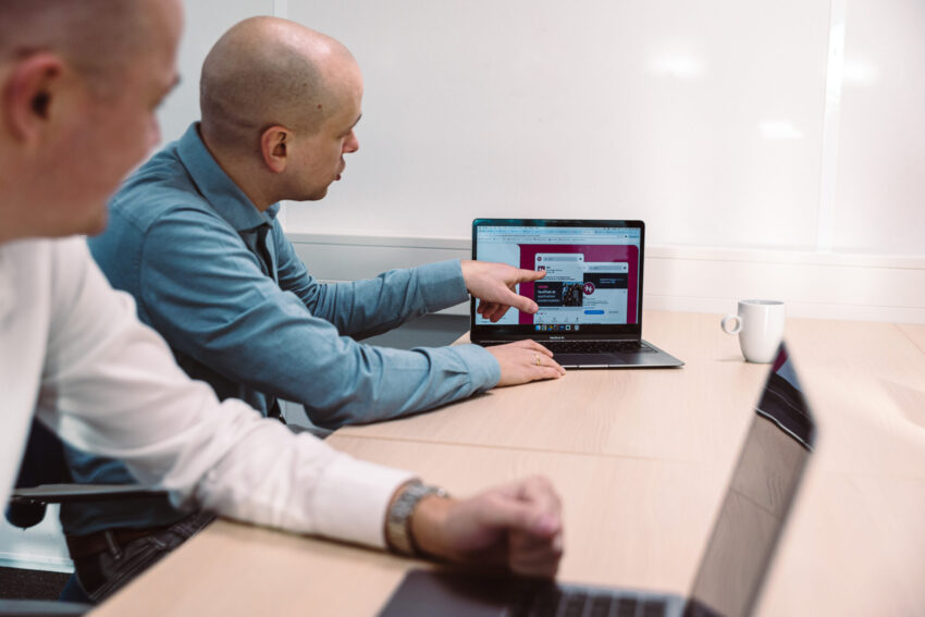 Two people with laptops at a desk.