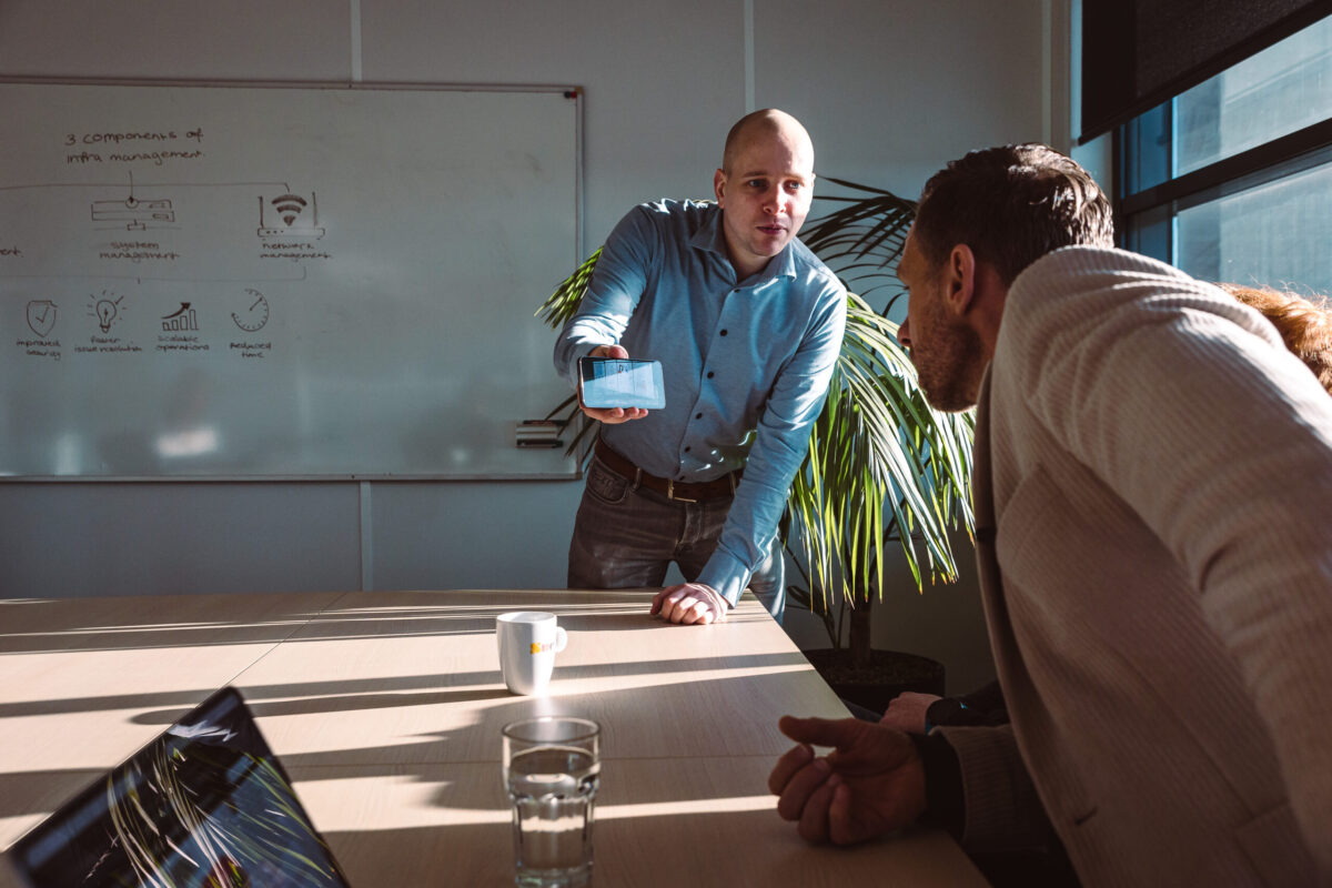 Two people. One person showing his phone.